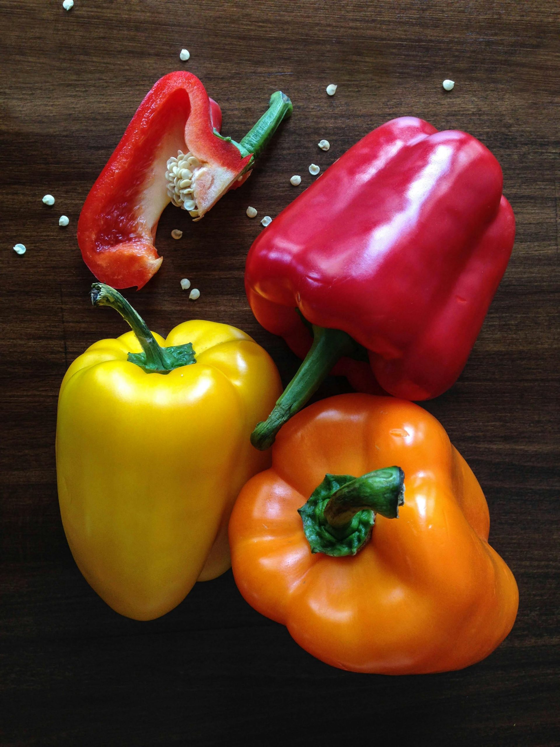 Three vibrant bell peppers on a wooden surface, perfect for cooking inspiration.